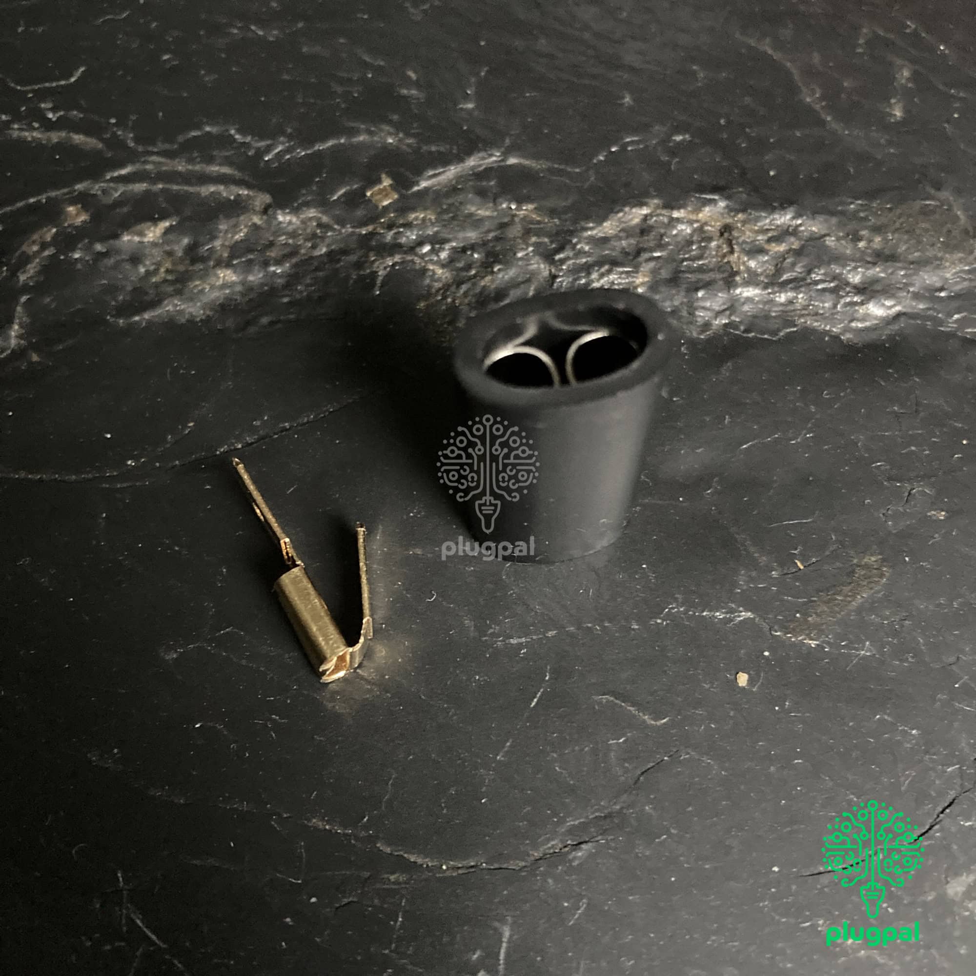 Silicone fuse holder with small metal fuse on black textured background, component for electrical safety in power strips or chargers. Suitable for reliable electrical connections and fuse replacement.