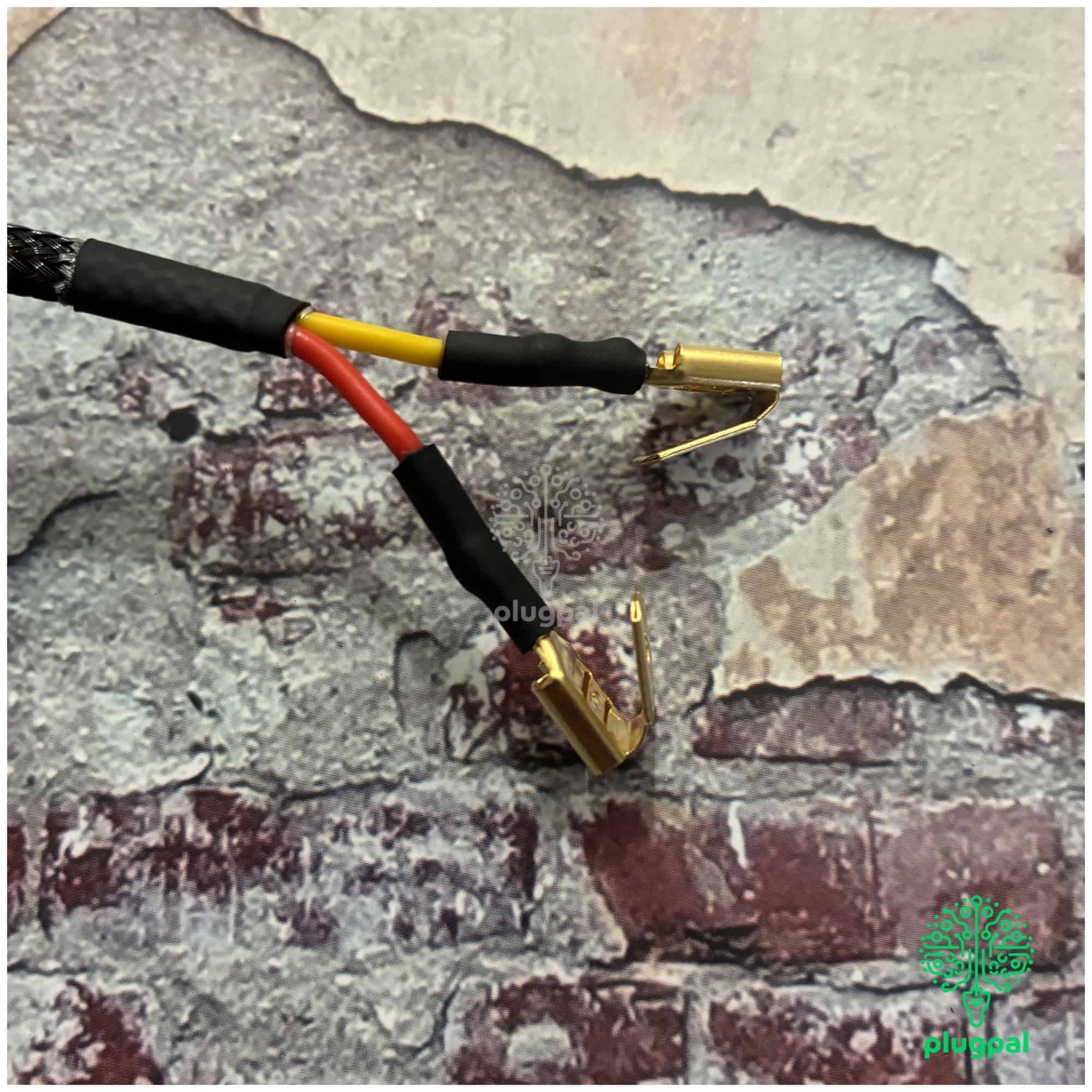 Close-up of a Ford 5V solid state voltage stabiliser with bracket, featuring red and yellow wires, mounted on a textured brick wall background.