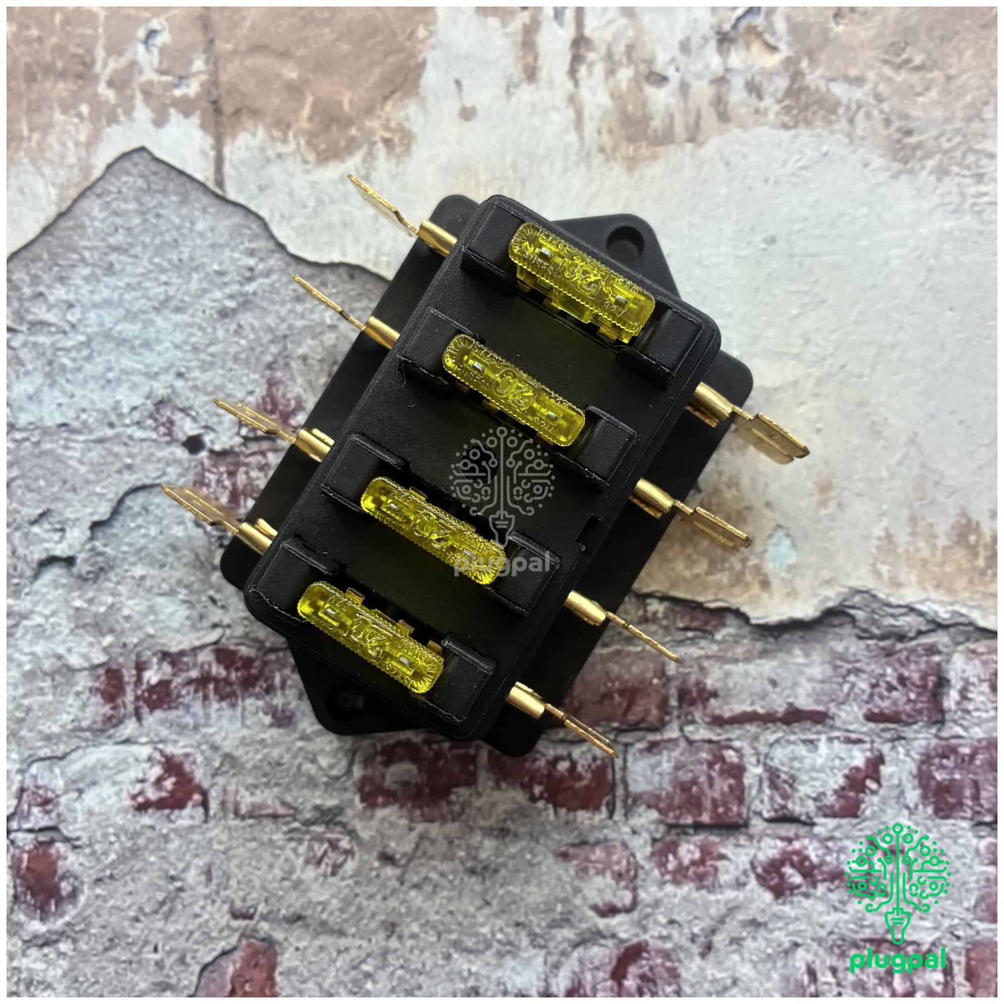 Close-up of a blade fuse box with yellow fuses and gold terminals, used in automotive electrical systems.
