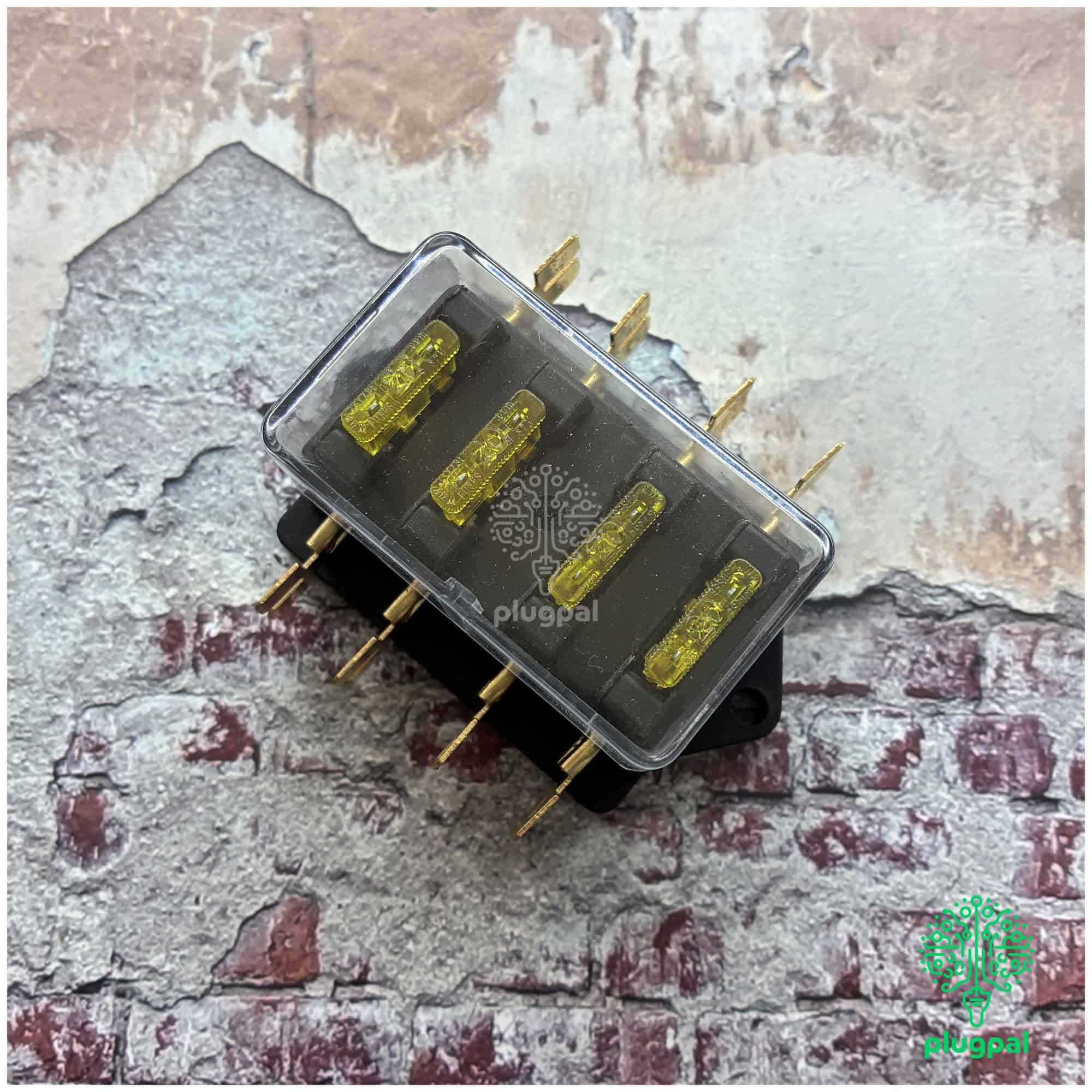 Close-up of a blade fuse box with yellow fuses and metal terminals, used in vehicle electrical systems for circuit protection.